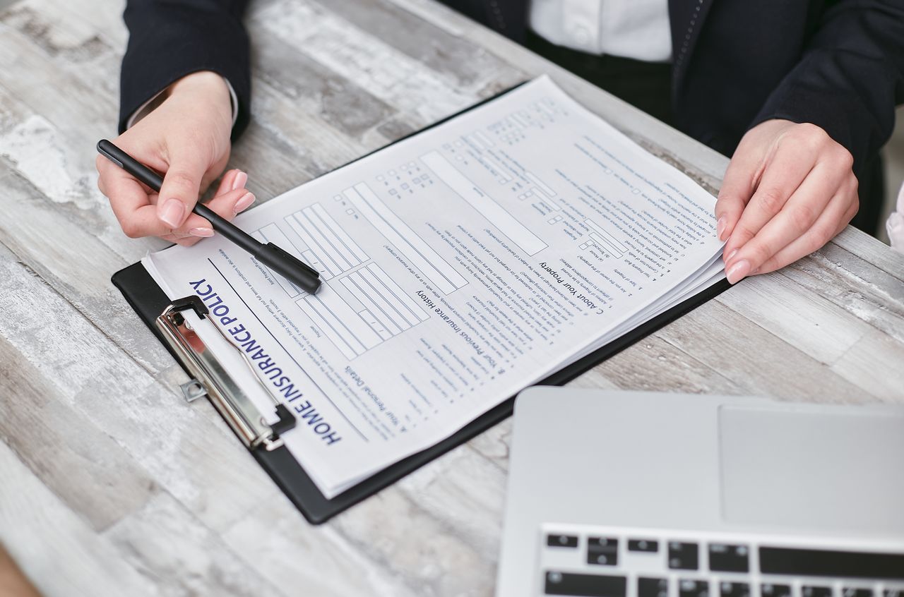 about-01 Close-up of hands reviewing a home insurance policy, emphasizing professionalism and finance.